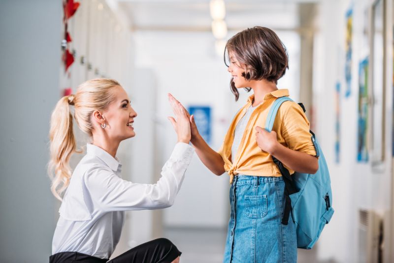 teacher high fiving a student at her level