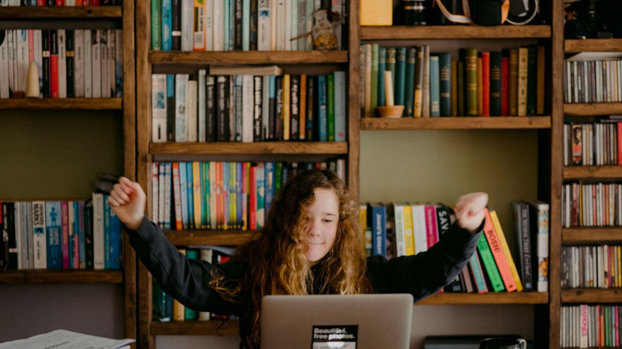 young girl celebrating while learning at her laptop