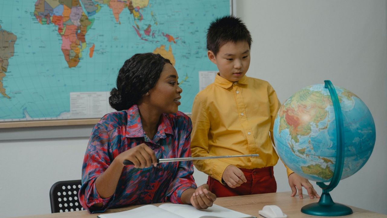 teacher and student looking at a globe