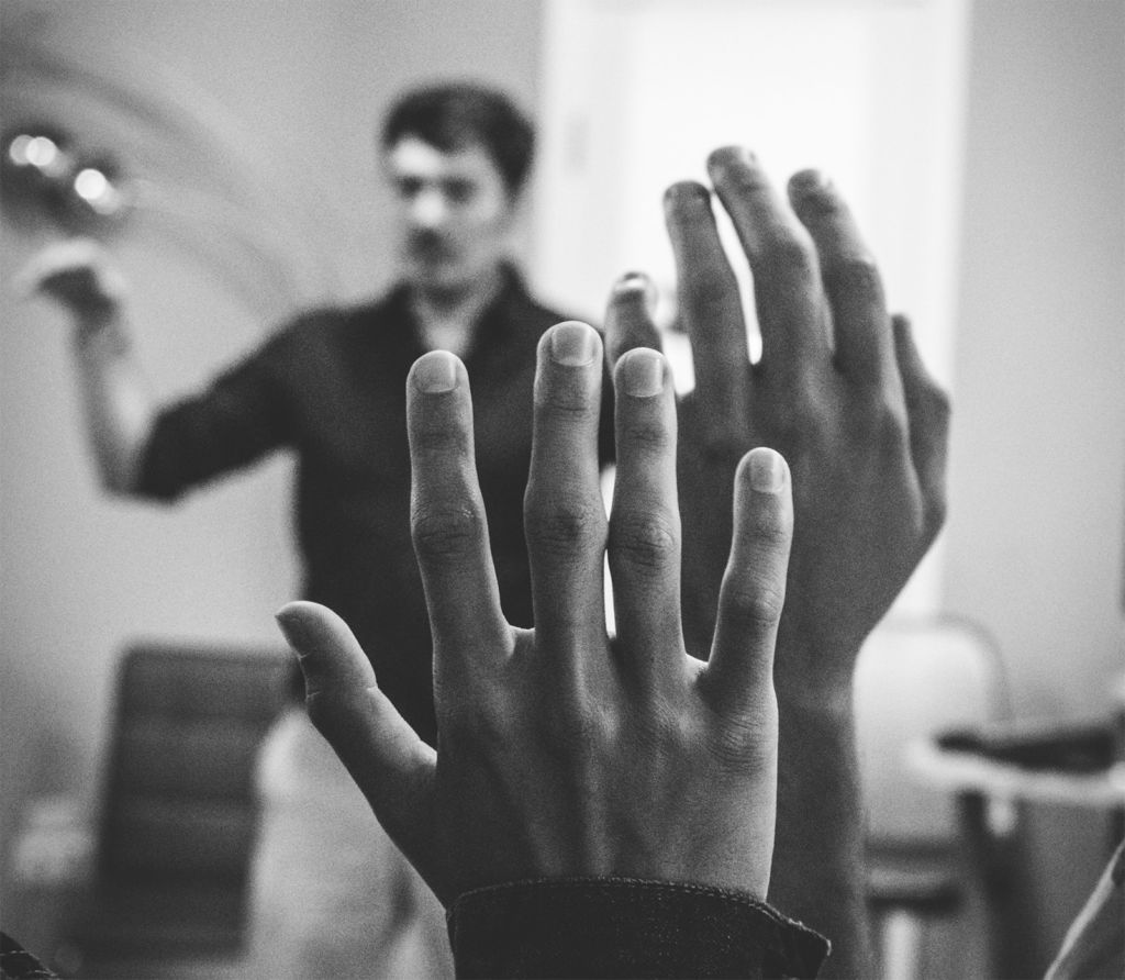 two raised hands, teacher talking in background