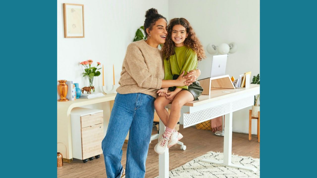 young girl sitting on a desk and woman hugging her