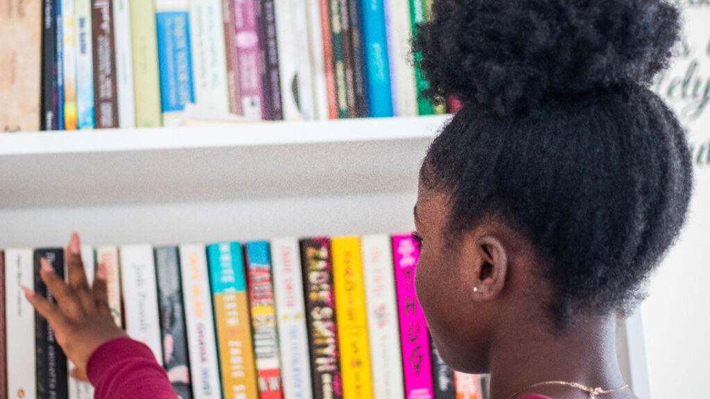 young girl looking at books on a shelf