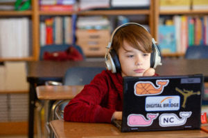 student working on computer wearing headphones