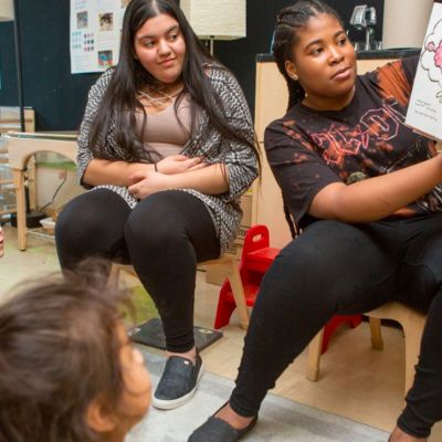 Student reading to younger students