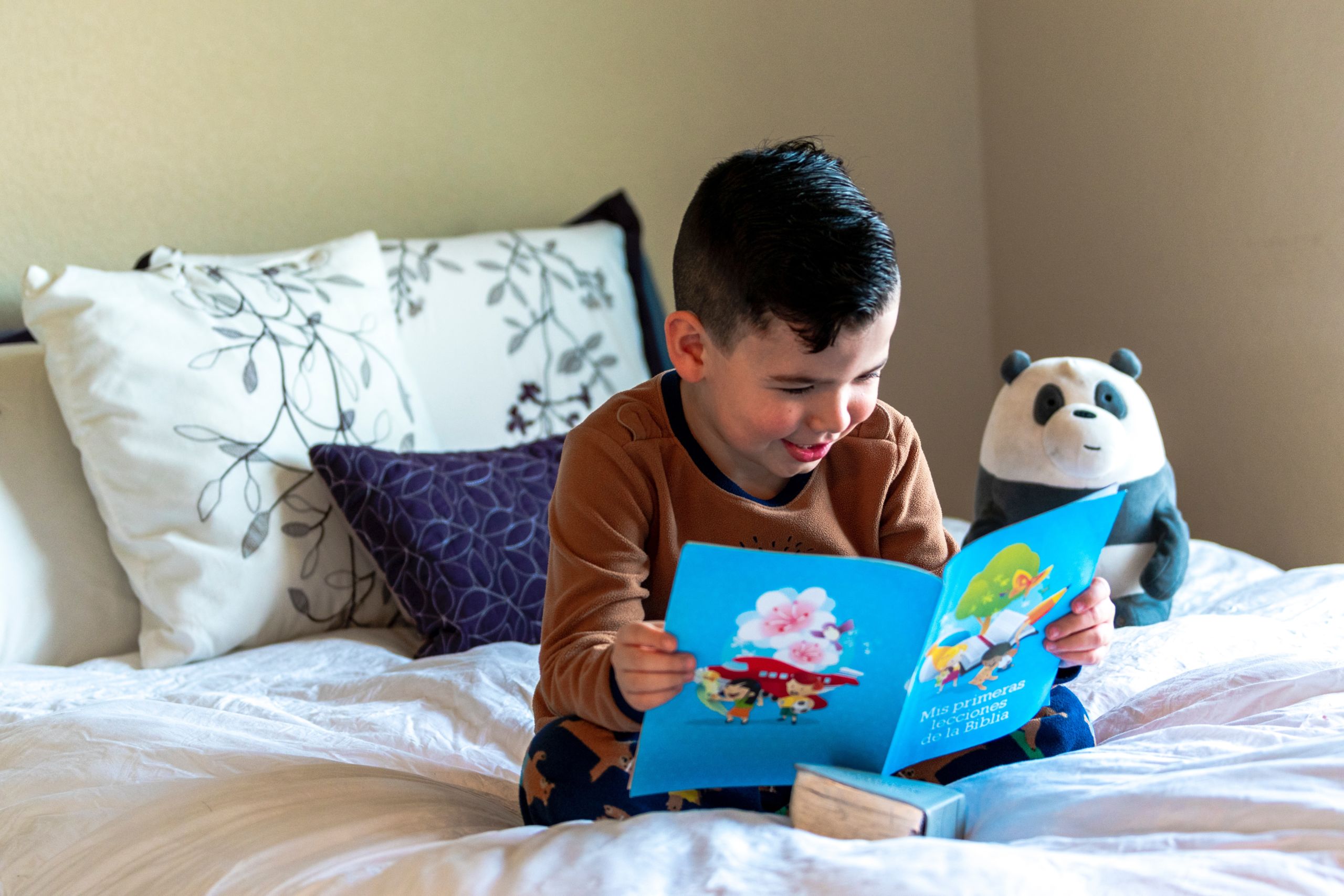 little boy sitting in bed reading a book