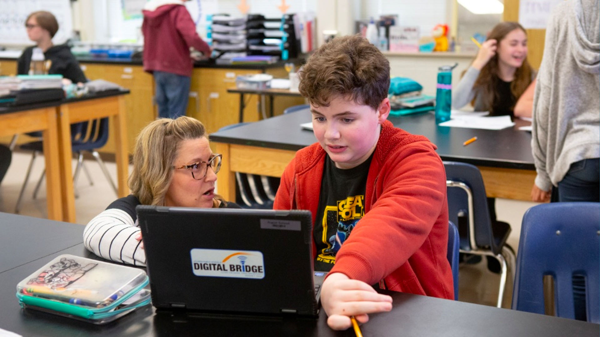 Teacher helping a student at a laptop