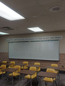 classroom with empty desks in front of a whiteboard