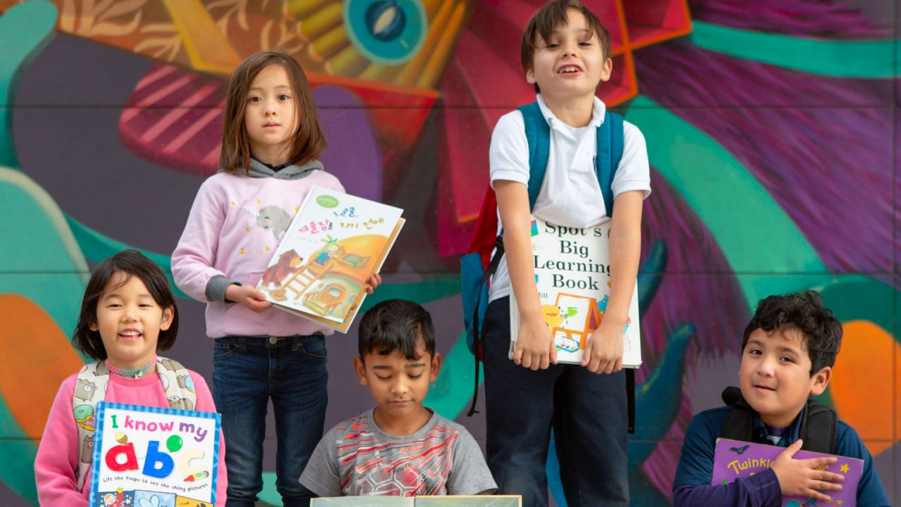Elementary students with books and school mural
