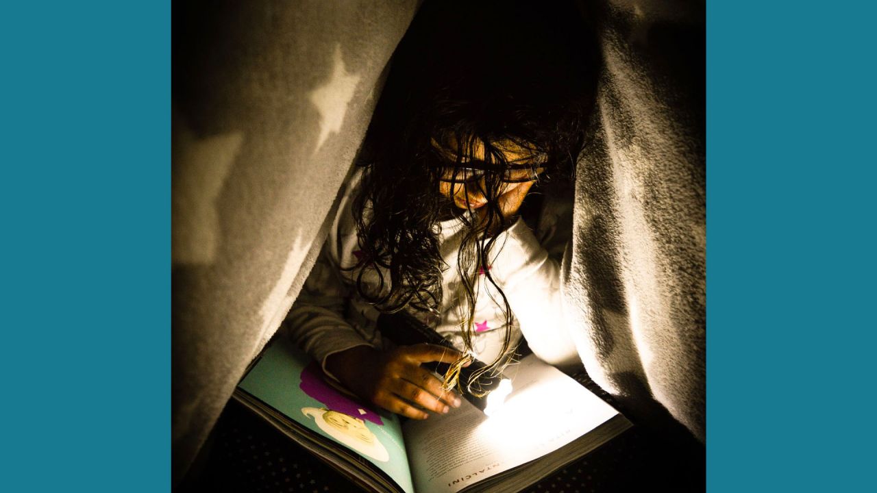 Student reading under a blanket.