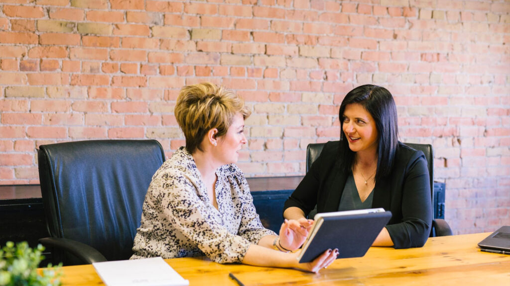 Two women discussing material in a meeting.