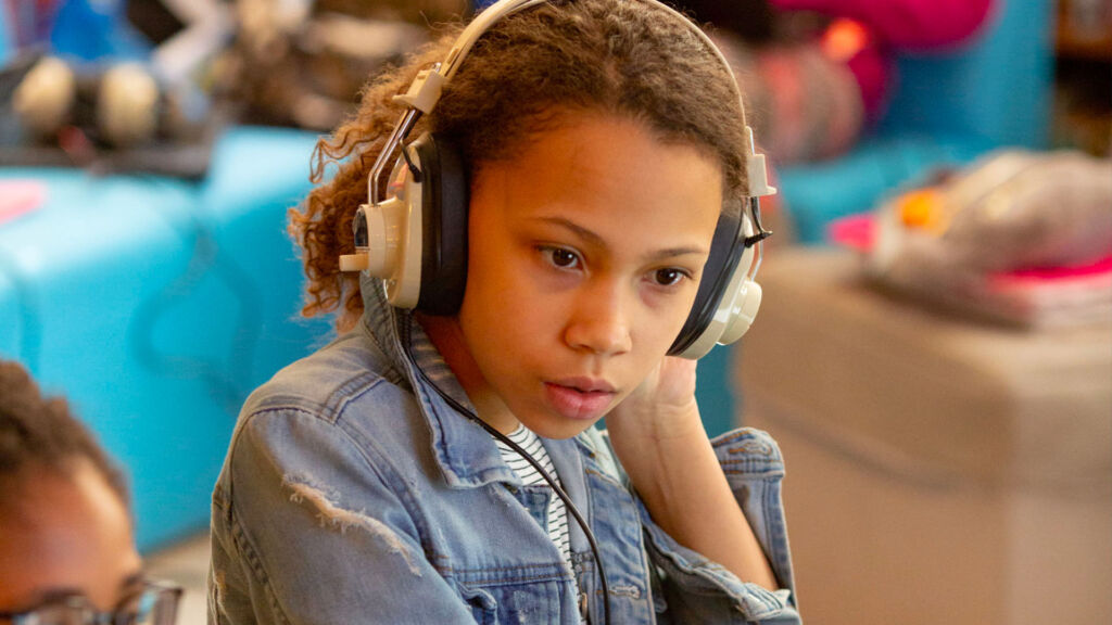 Young female student listen to music in class.