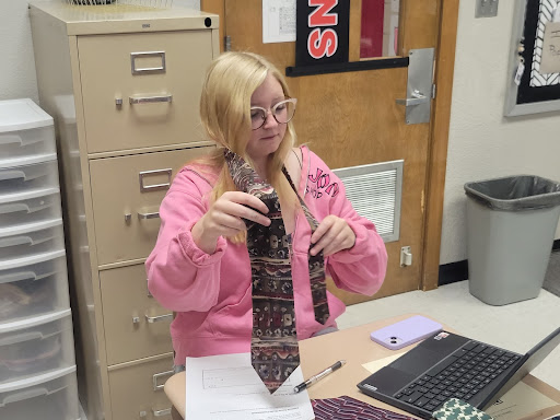 A student showing how to tie a tie.