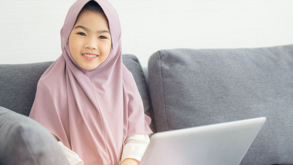 Young girl sitting on a couch with a laptop.