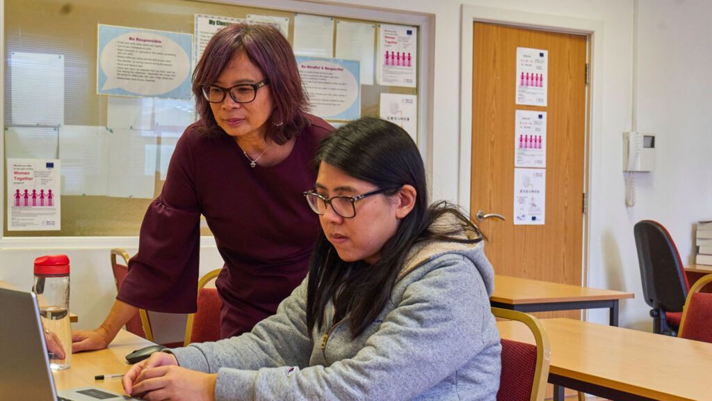 Teacher and student reviewing content on a computer.