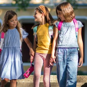 Three students holding hands outside.