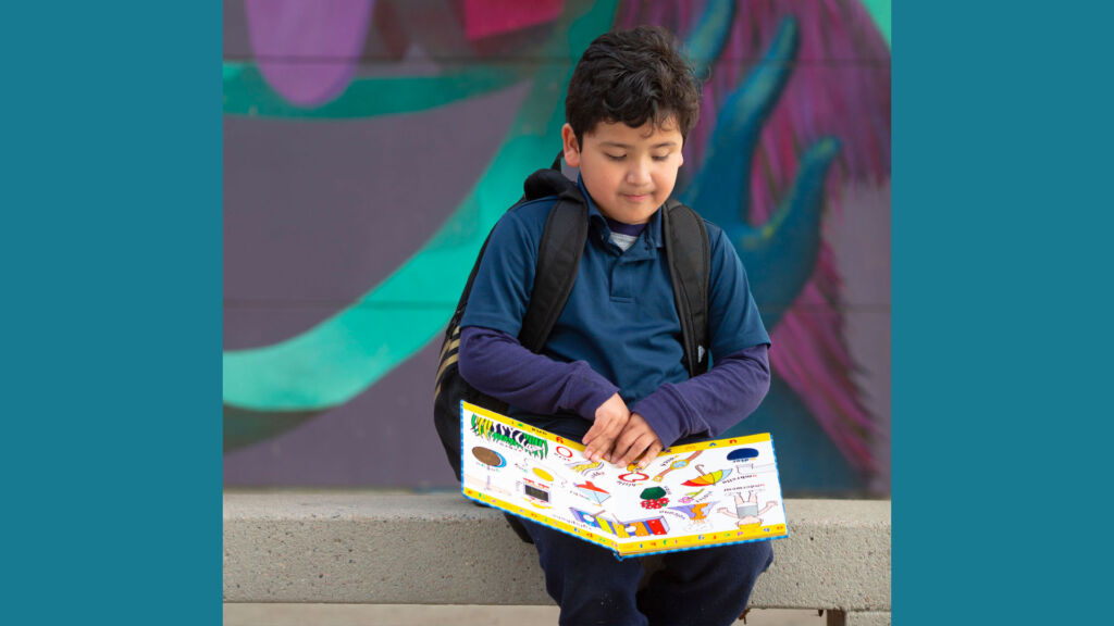 First Grade boy reads book outside.