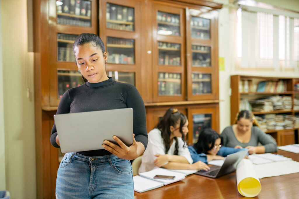 Woman standing and holding a laptop.