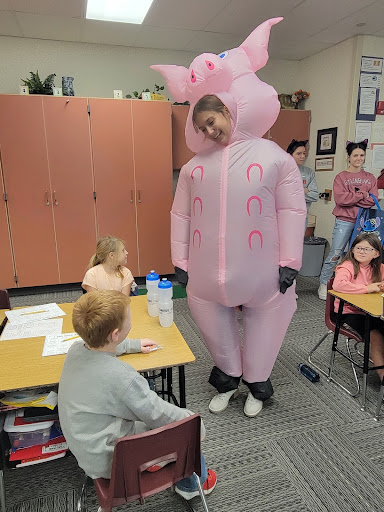 Student in costume with elementary students.