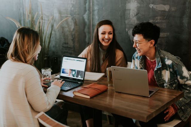 Three people sitting at a table with their laptops.