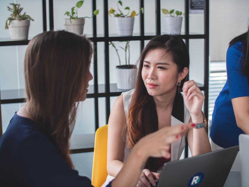 Two women talking, sitting down at a table.