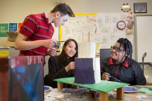 Boy high schooler and two girls build a speaker