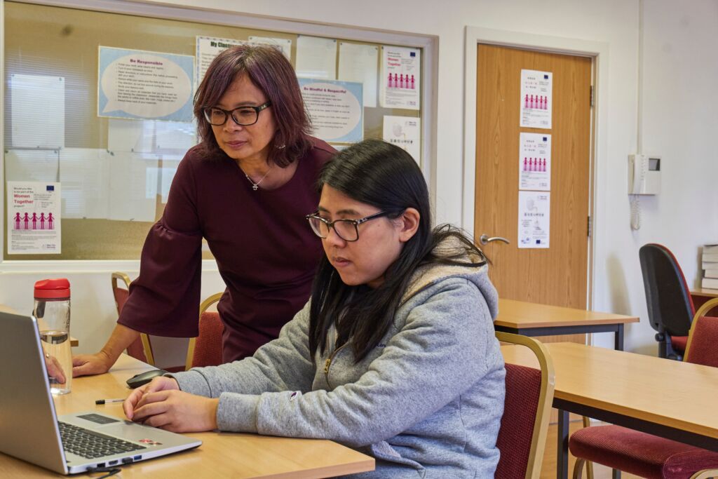 A teacher and a student working together at a table with a laptop.