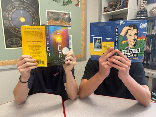 Students holding books up and reading.