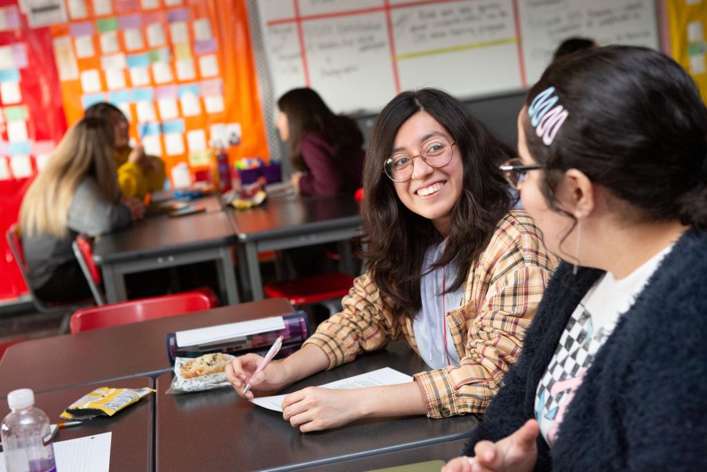 Two high school students discuss their research topics together.