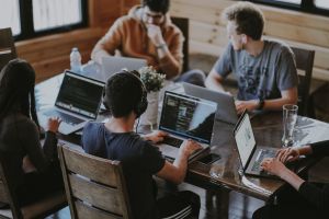 People sitting at a table, using their laptops.