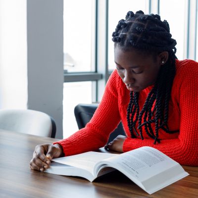 Female student reading a book in a classroom.