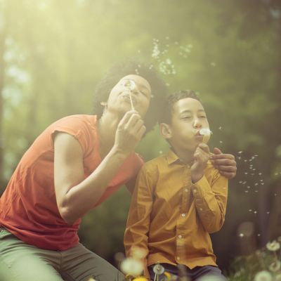 Adult and child blowing on dandilions.