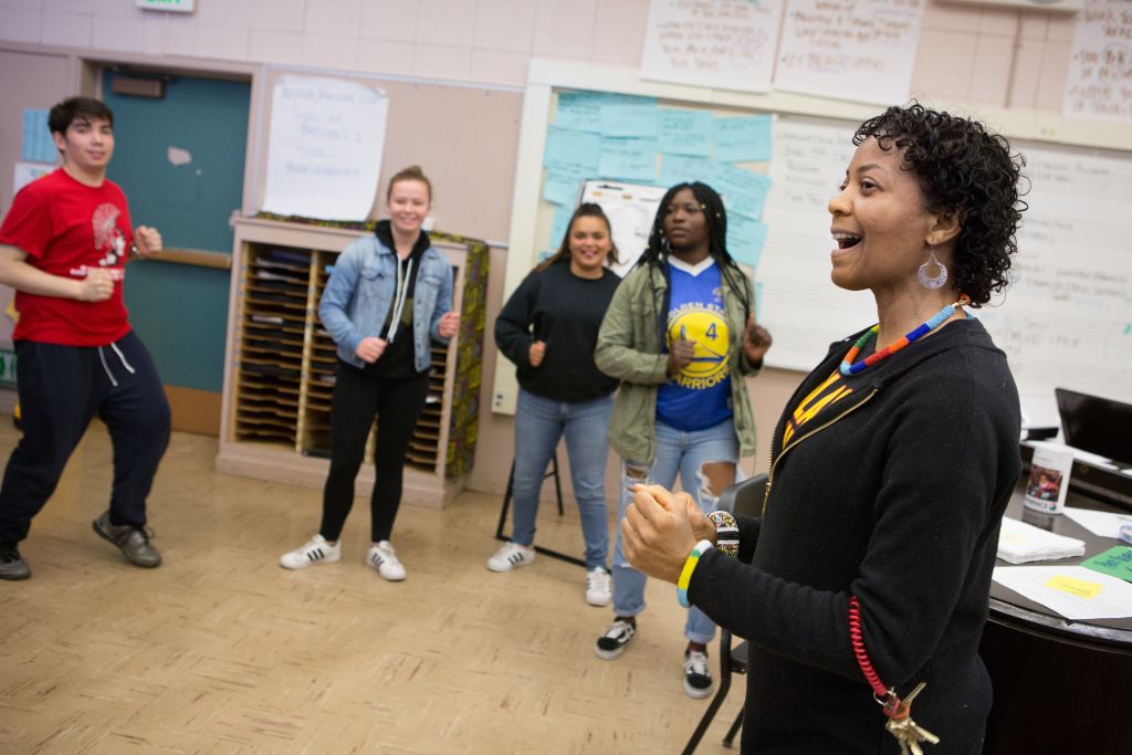 A music teacher leads choir students in a warm-up exercise.