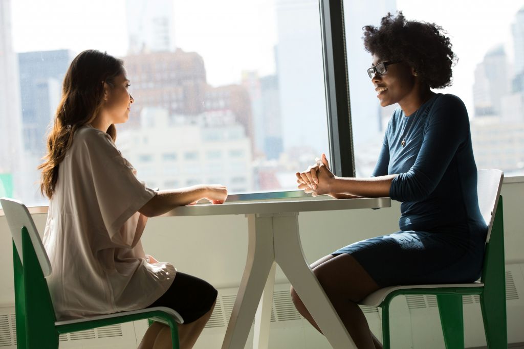 Two women sitting at a table and talking.