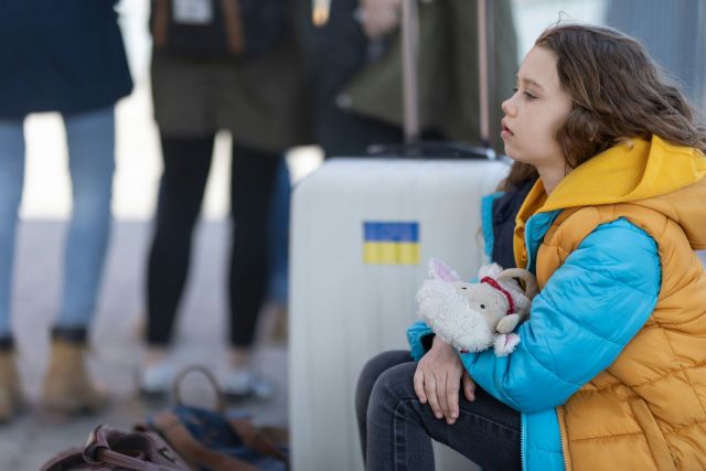 Little girl sitting down, holding a stuffed animal.