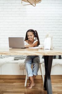 Child sitting at a desk, using a laptop.