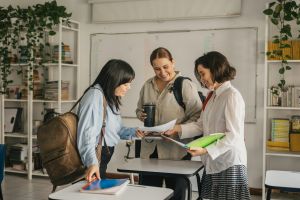 Three teachers standing together discussing some paperwork.