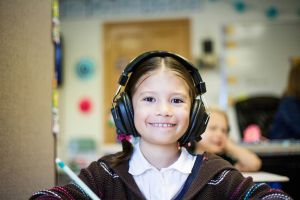 Child wearing headphones and smiling.