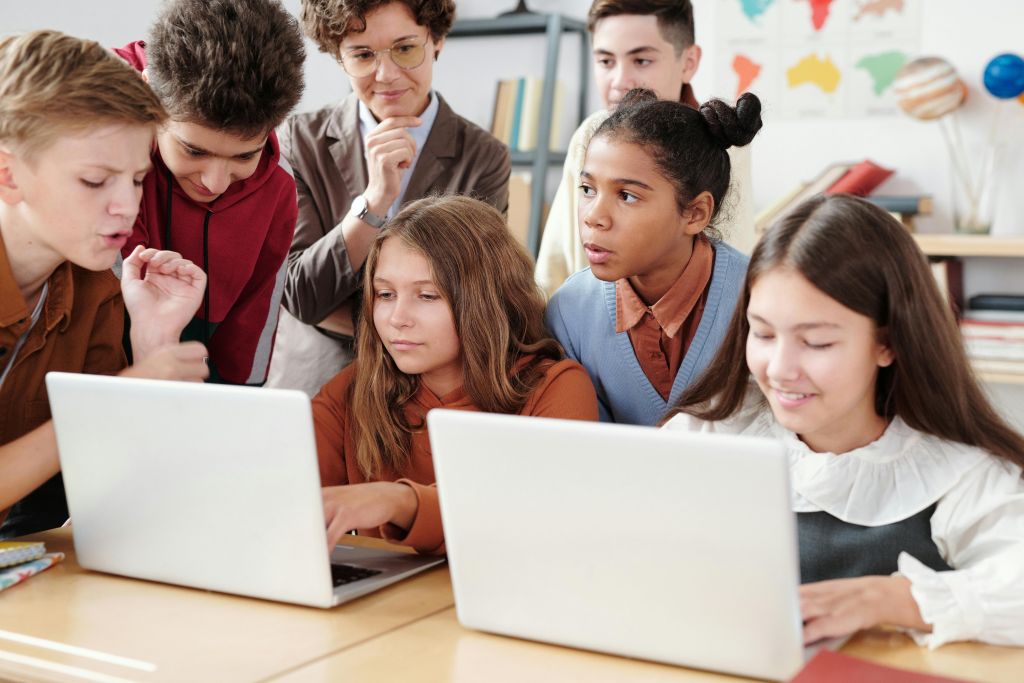 Students around laptops in a classroom.