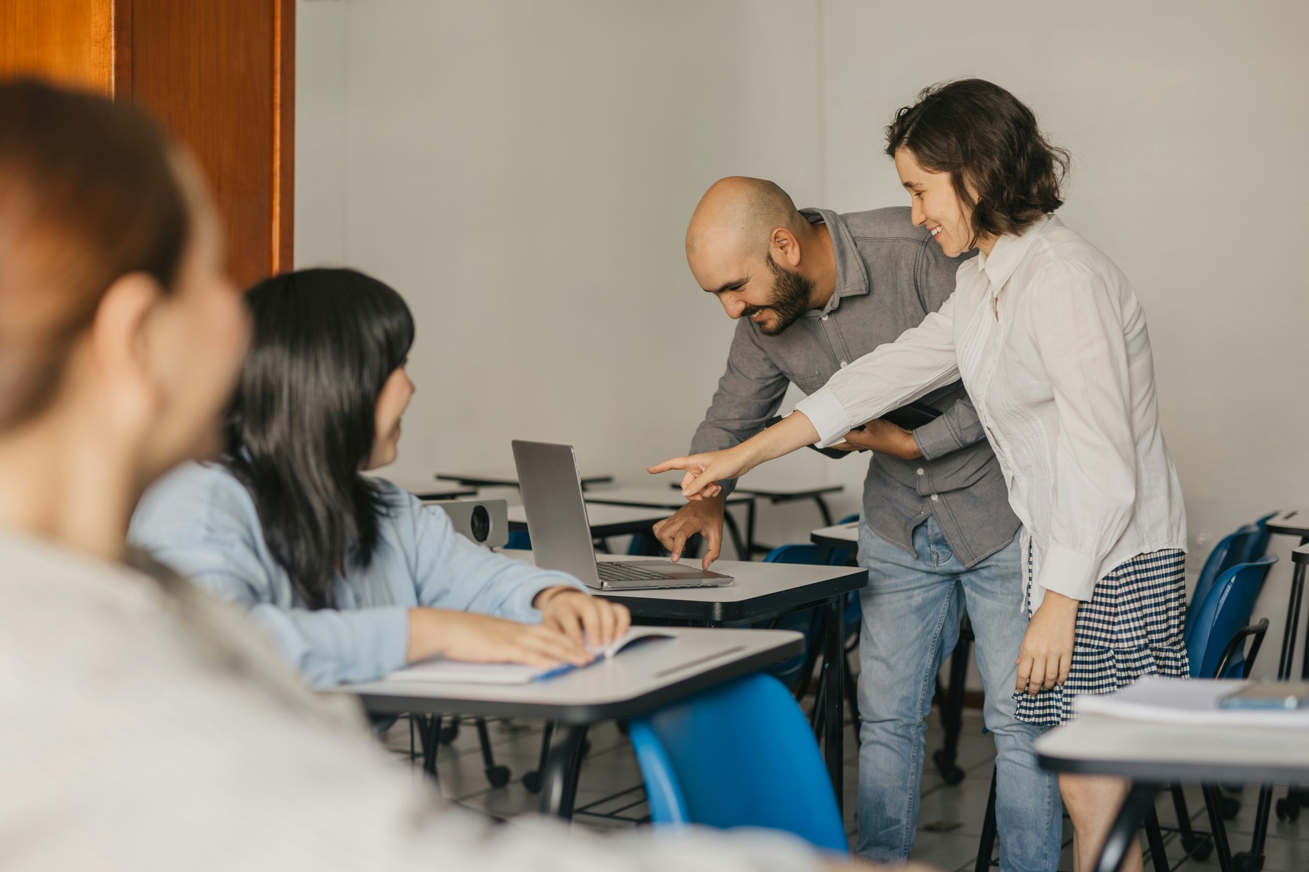 Teacher looking at a laptop with some students.