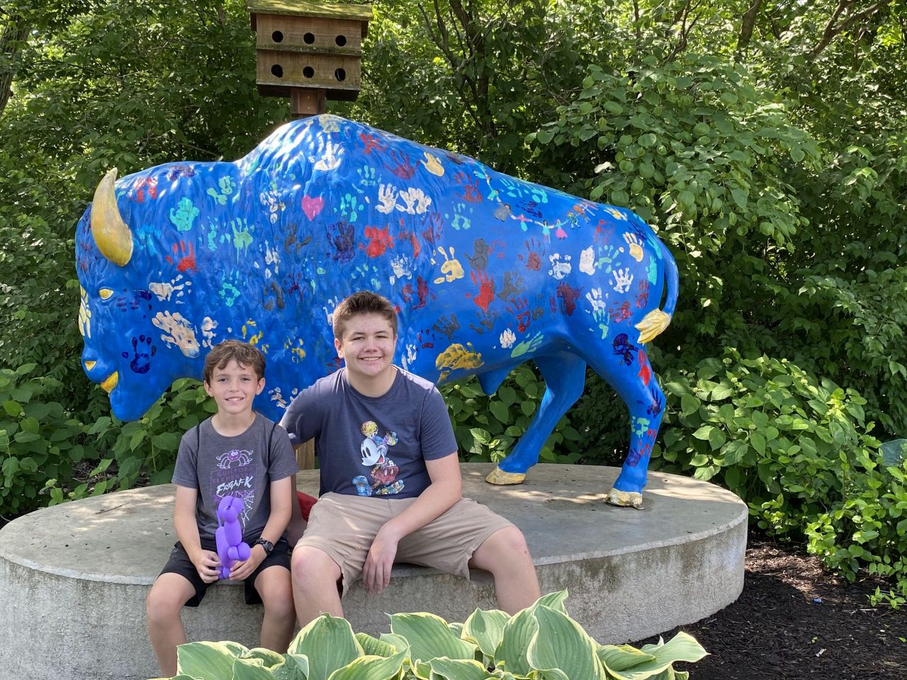 Two kids in front of a buffalo statue.