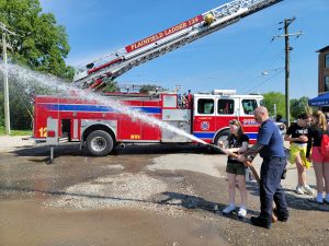 Firefighter showing a student how to use the firehouse. 