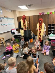 Two students dressed up as hot dogs, visiting elementary students.