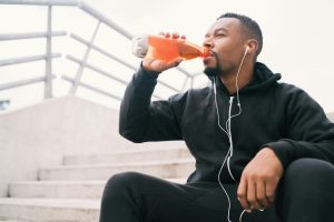 A man drinking a drink while taking a sit down.