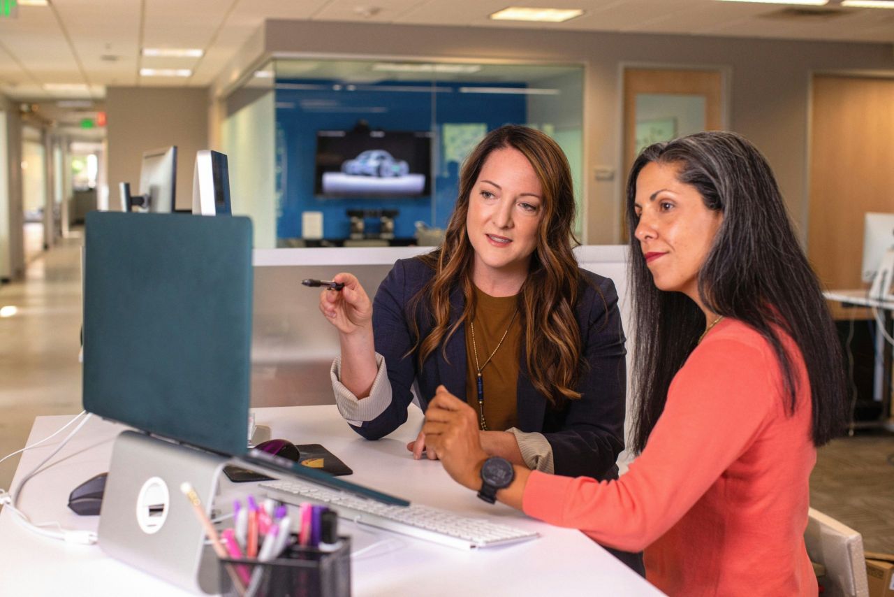 Two people working together and checking things on a laptop.