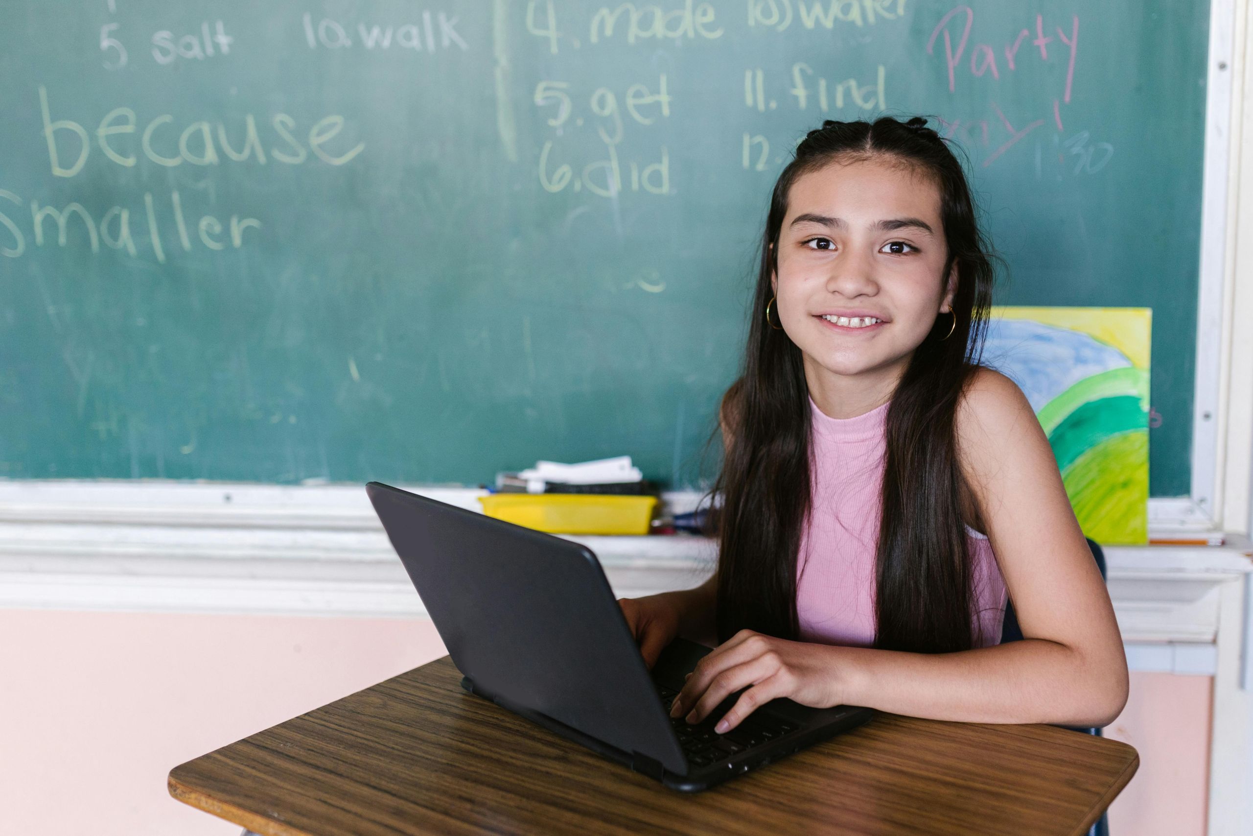 Female student sitting with her laptop, at a desk, in the classroom.