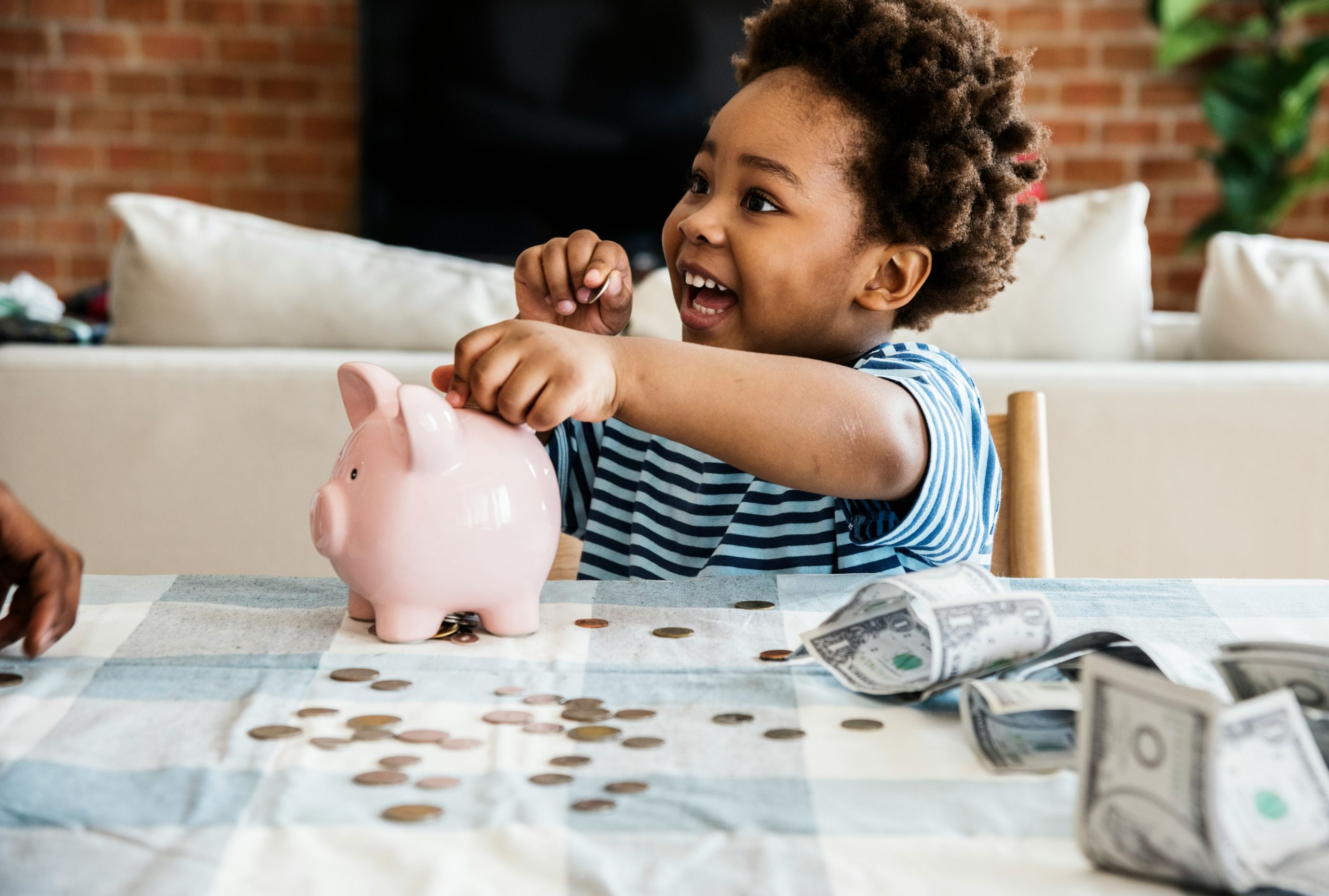 A happy child adding money to a piggy bank.
