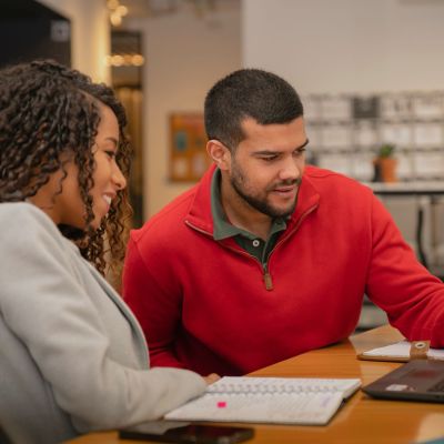 Two people talking over a laptop.