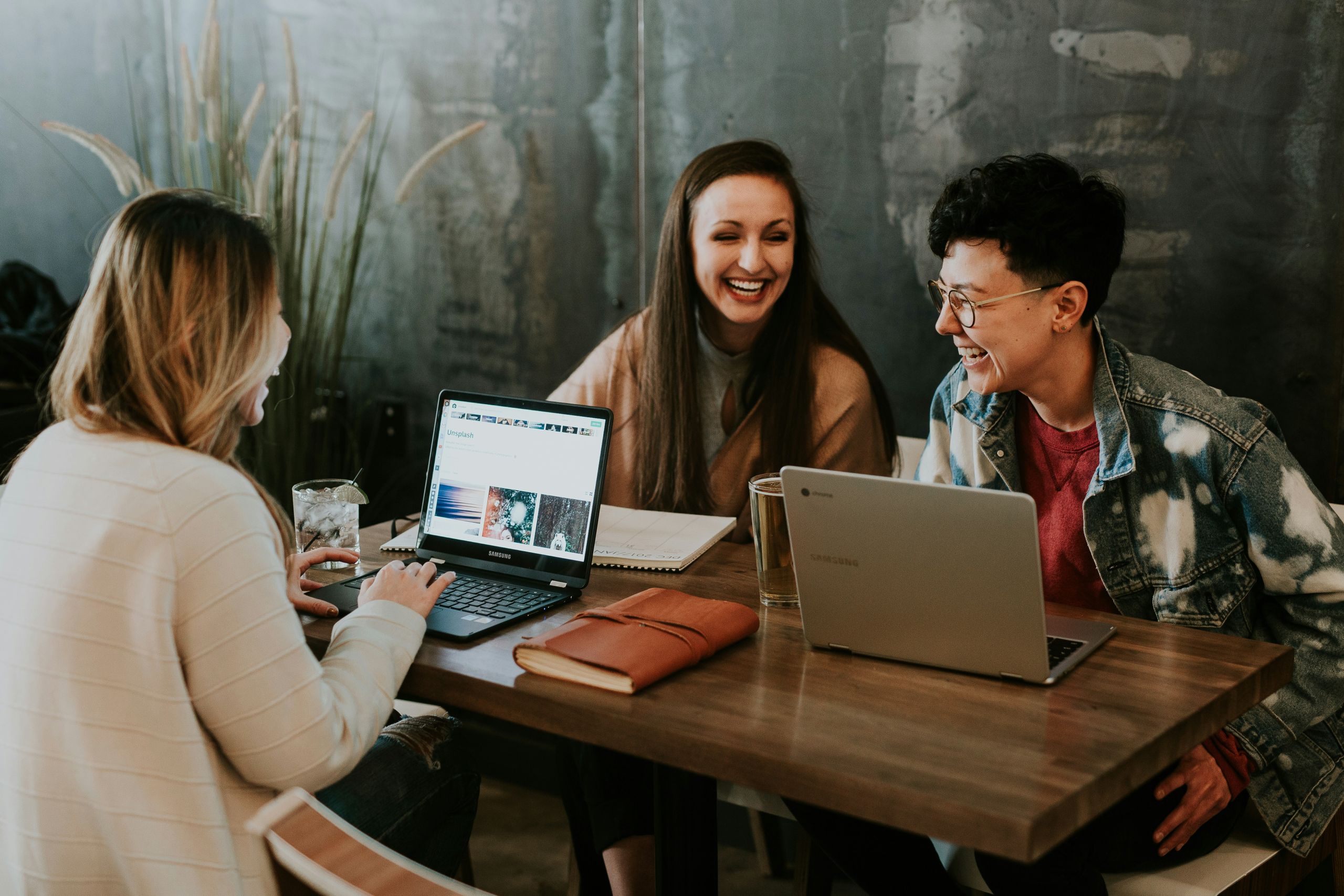 3 adults working together at a table with a computer in front of each 3 adults working together at a table with a computer in front of each