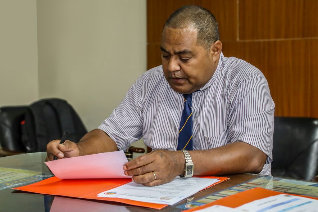 Dark skinned man reading paperwork while sitting at a table