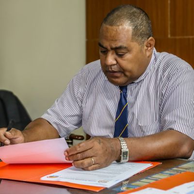Dark skinned man reading paperwork while sitting at a table
